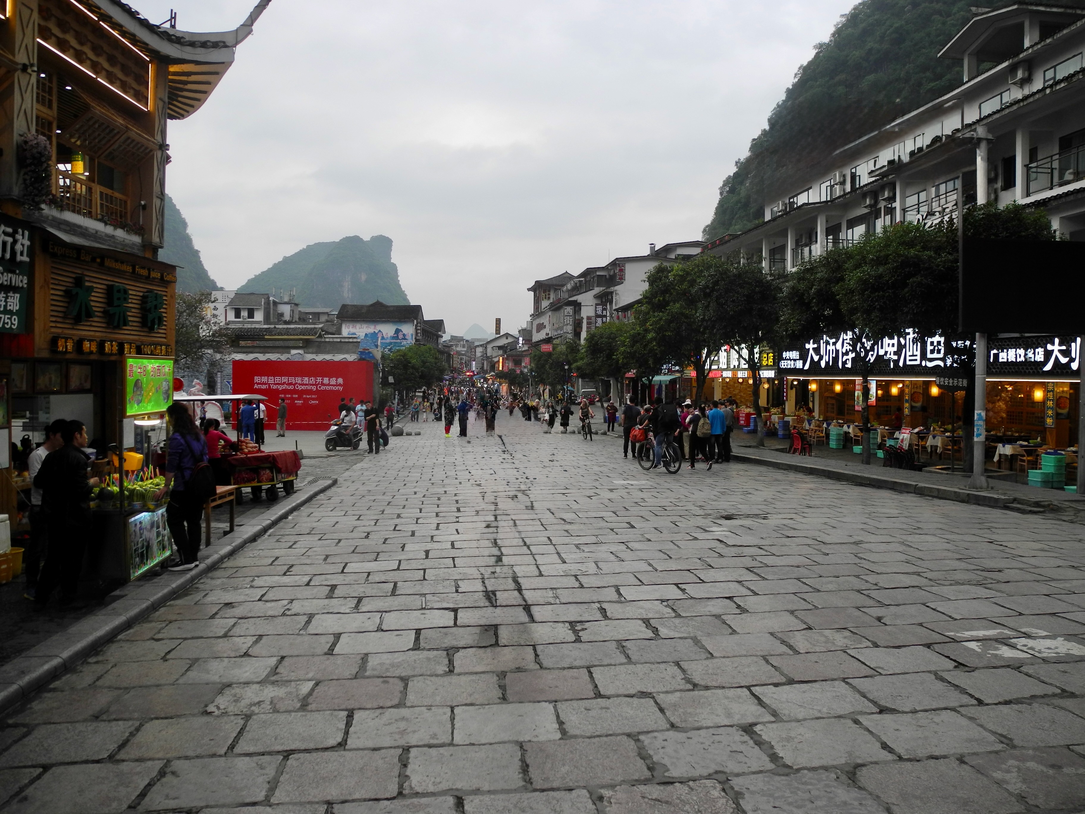 Rue piétonne de Yangshuo au crépuscule avec les pics karstiques du Guangxi en arrière-plan