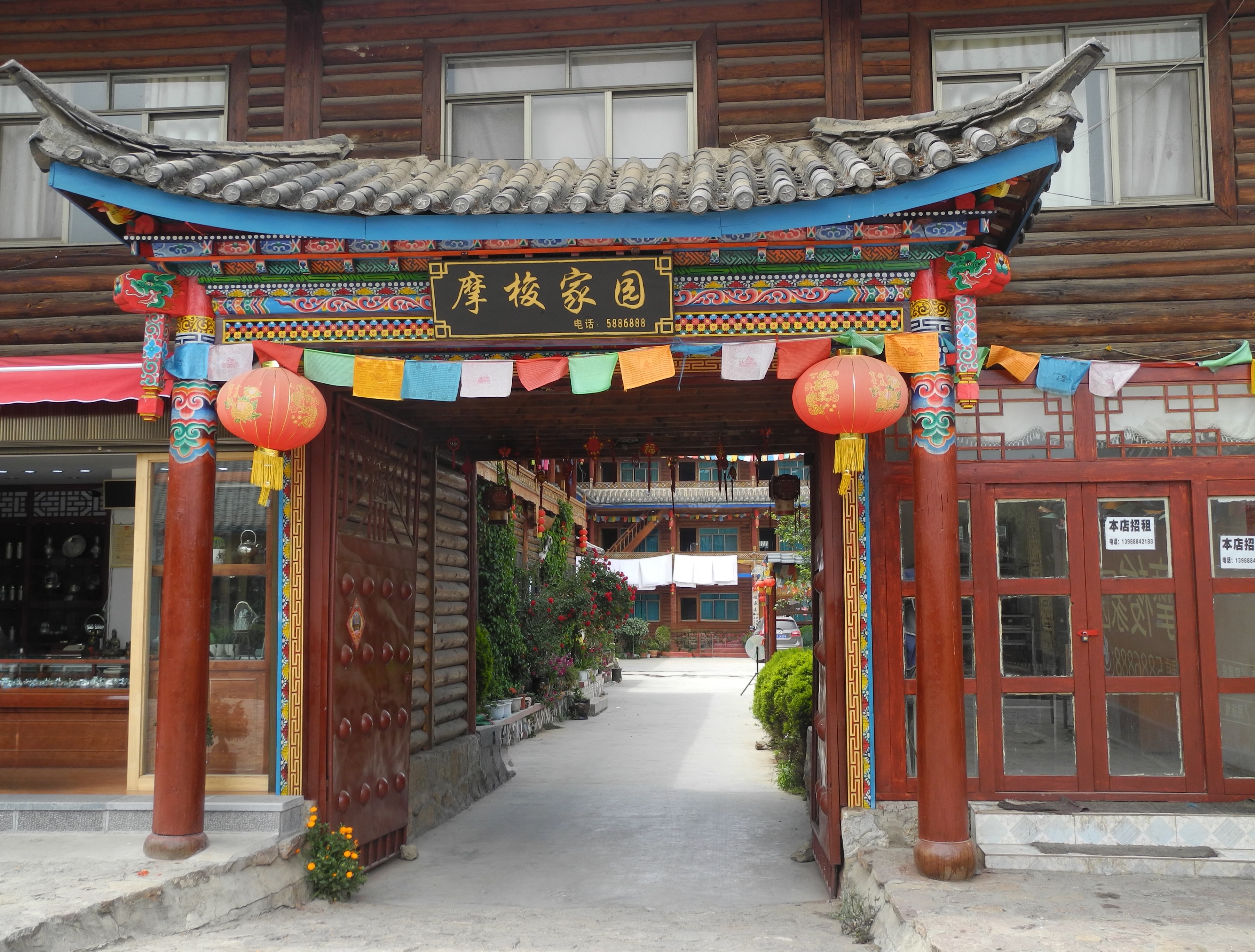 Entrée décorée d'une maison traditionnelle Mosuo au bord du lac Lugu, drapeaux de prières et lanternes rouges