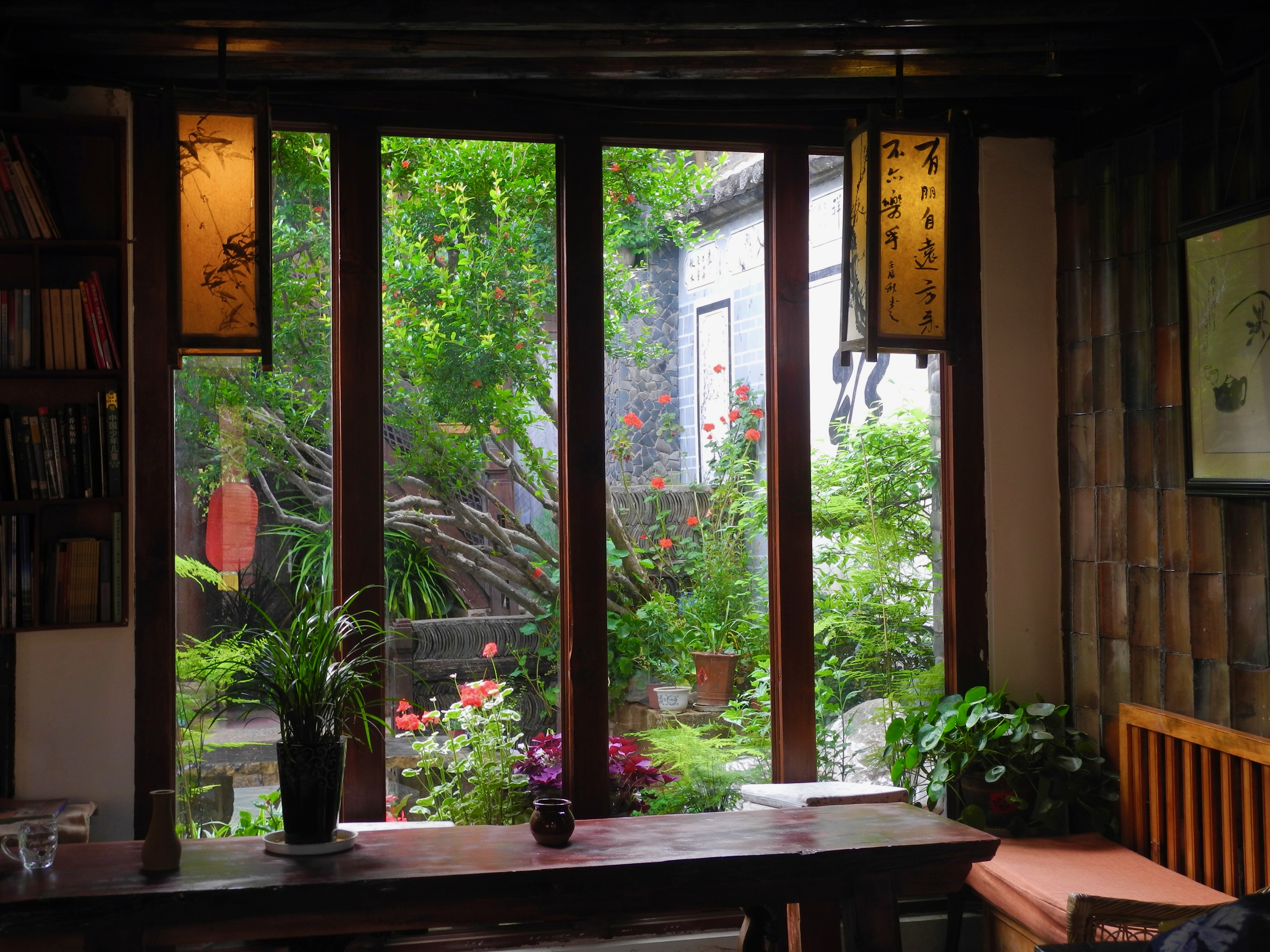 Fenêtre en bois d'un café de Shaxi ouvrant sur un jardin fleuri